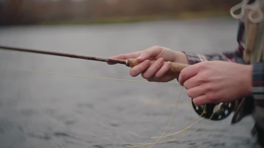 Person holding fly fishing rod with yellow line over water