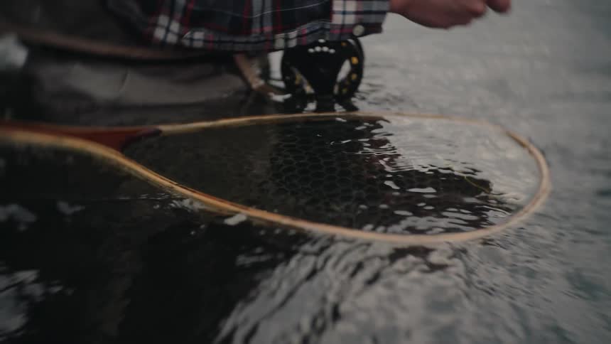 Fishing net rests partially submerged in the water as a person handles the gear