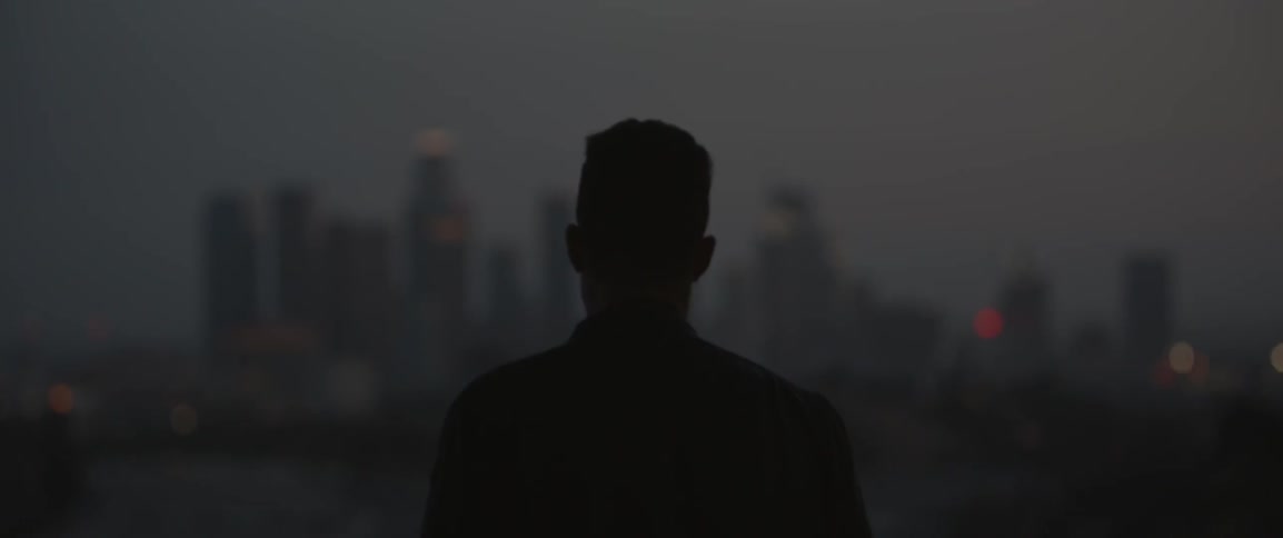 A man walks out over a city at dawn