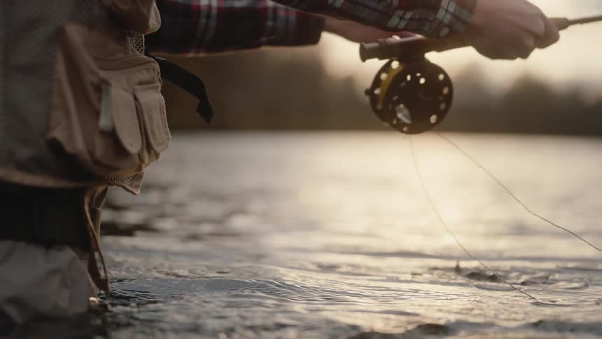 The man fly fishes while standing waist high in water