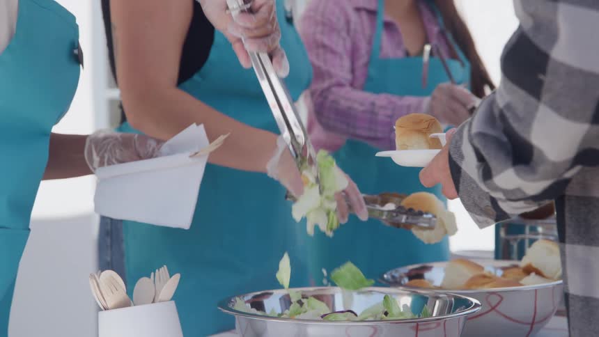 Food distribution at community event with volunteers serving salad and bread to attendees