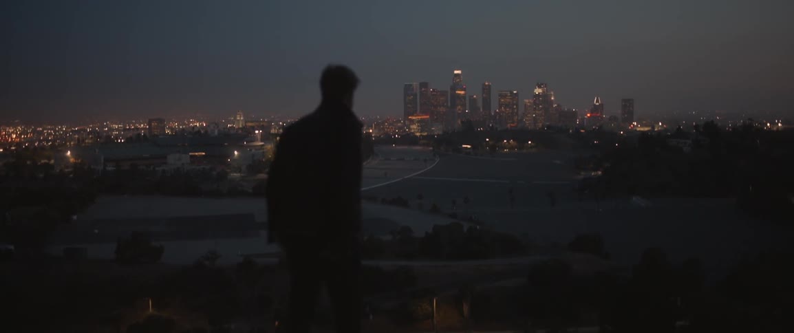 A man looks out over a city at dawn