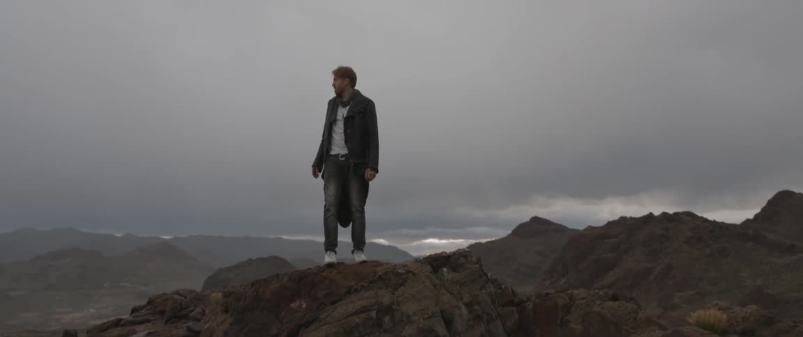 A man tops a mountain and looks around