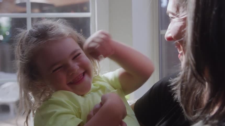 The mother tickles her daughter at home
