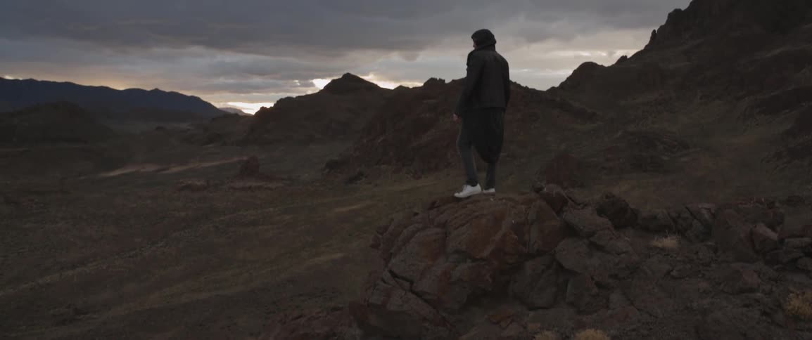 A person stands on a rocky ledge and looks around