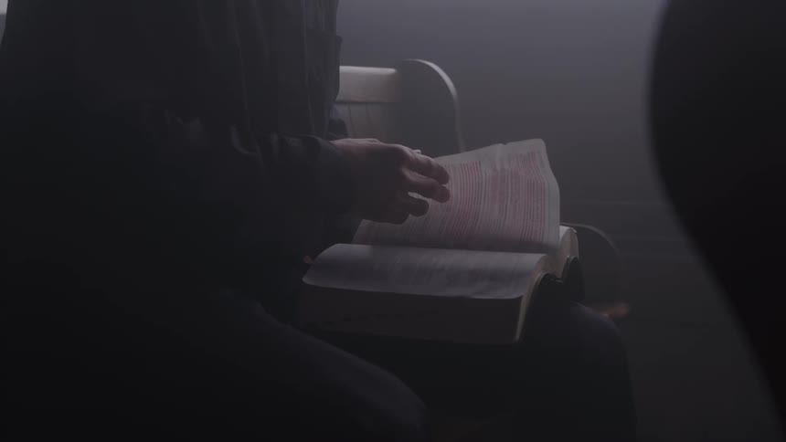 A person sitting in a pew reading a bible