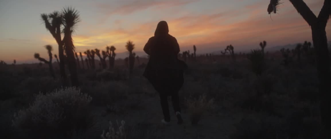 Man walking towards the sunset horizon in a desert area