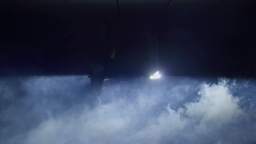 This short video clip features two bright spotlights shining downward from a dark ceilingthe light illuminates a large amount of fog or smoke billowing up from below creating an atmospheric theatrical effect