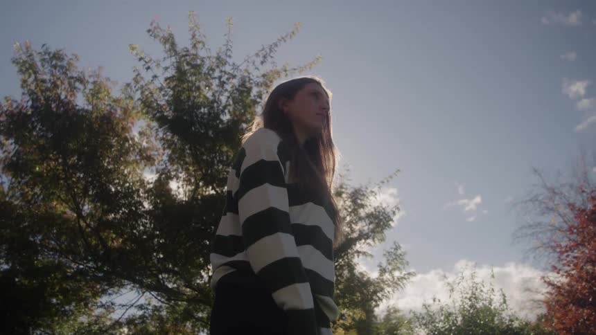 A woman standing outdoors on a sunny day