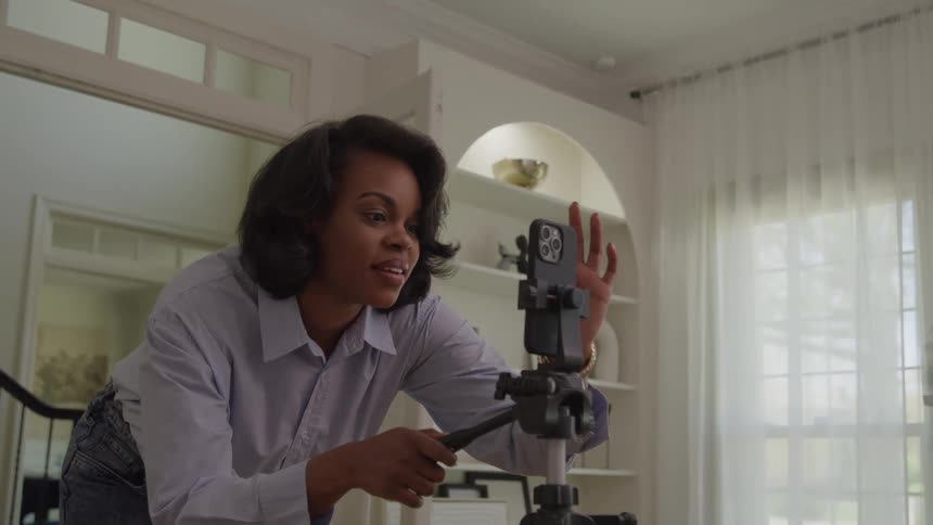 The woman is setting up her cell phone on a tripod