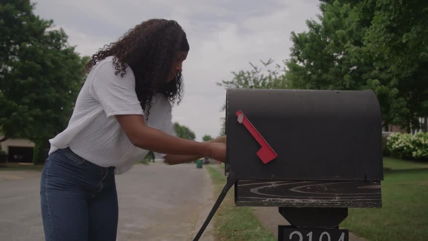 A woman getting mail out of a mailbox