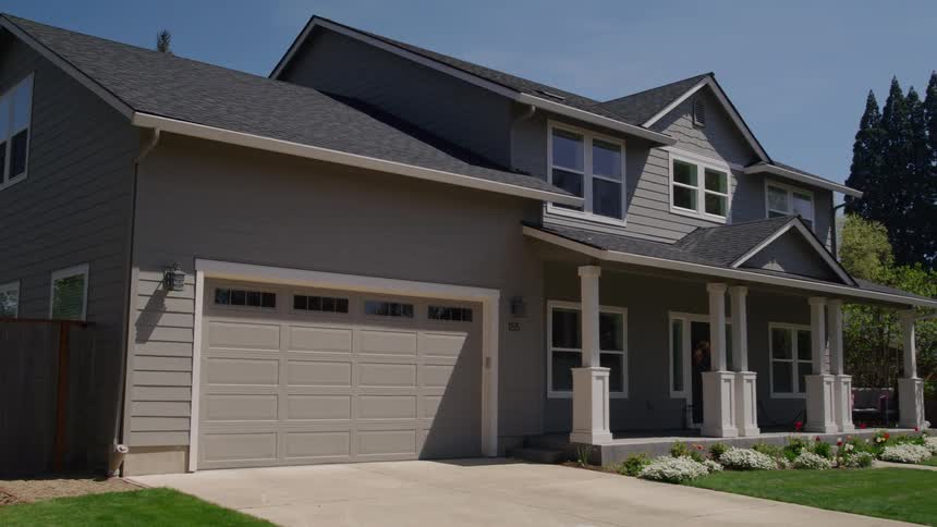 Twostory suburban house with double garage and decorated porch under clear blue sky