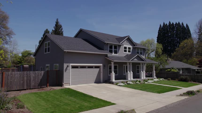 Twostory suburban house with gray exterior manicured yard and twocar garage