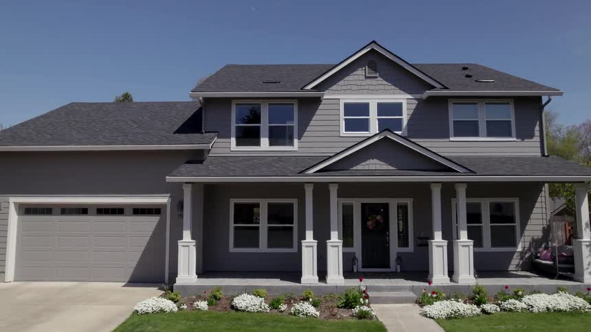 Modern twostory house with dark gray roof flowered yard and spacious garage