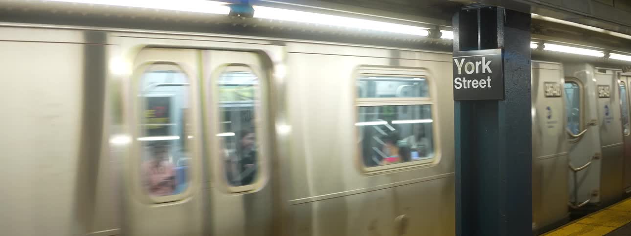 Passengers ride in a subway train passing through a station at york street