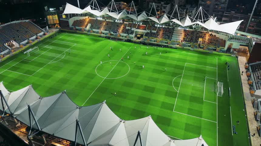 Stadium lit up shows an ongoing soccer match viewed from above