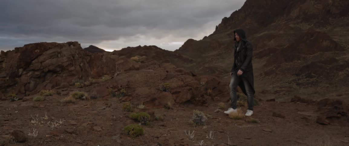 A man walks on a rocky hill on a cloudy day
