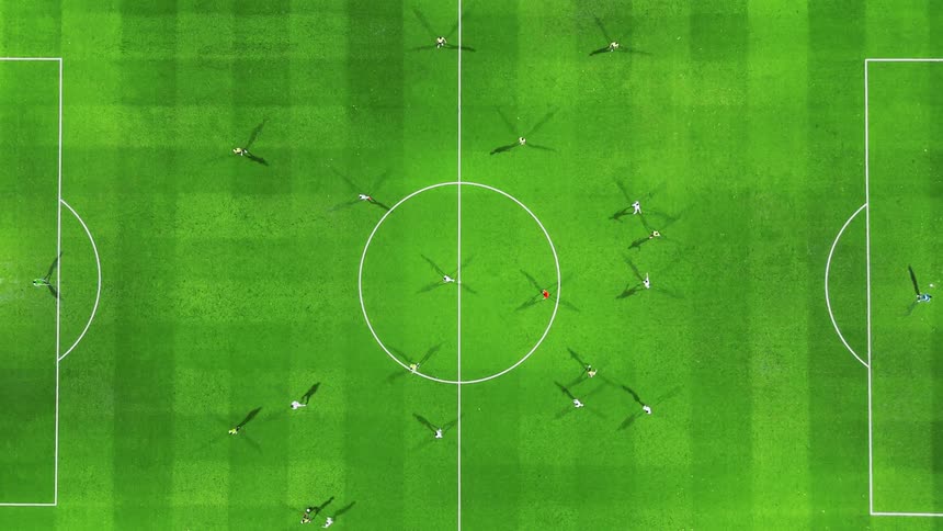 Aerial view of a group of players playing soccer on a bright green field