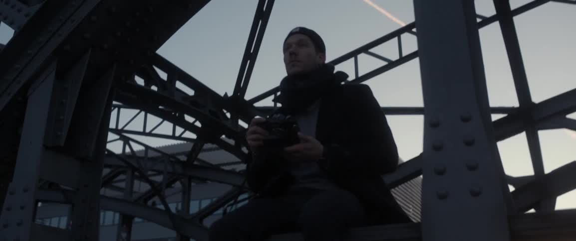 A man is sitting on the awning of a bridge