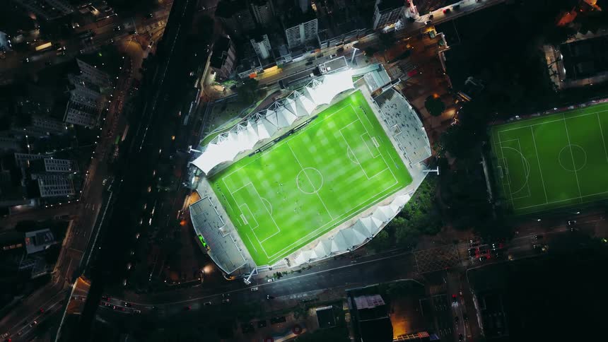 Illuminated stadium seen from above highlights a soccer match in progress in the city
