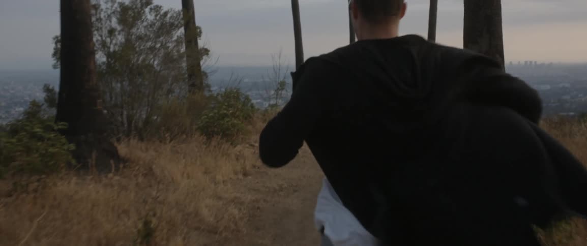 Man runs on a dirt path towards the ocean