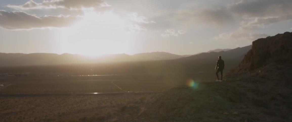 A man stands on a hill overlooking a valley