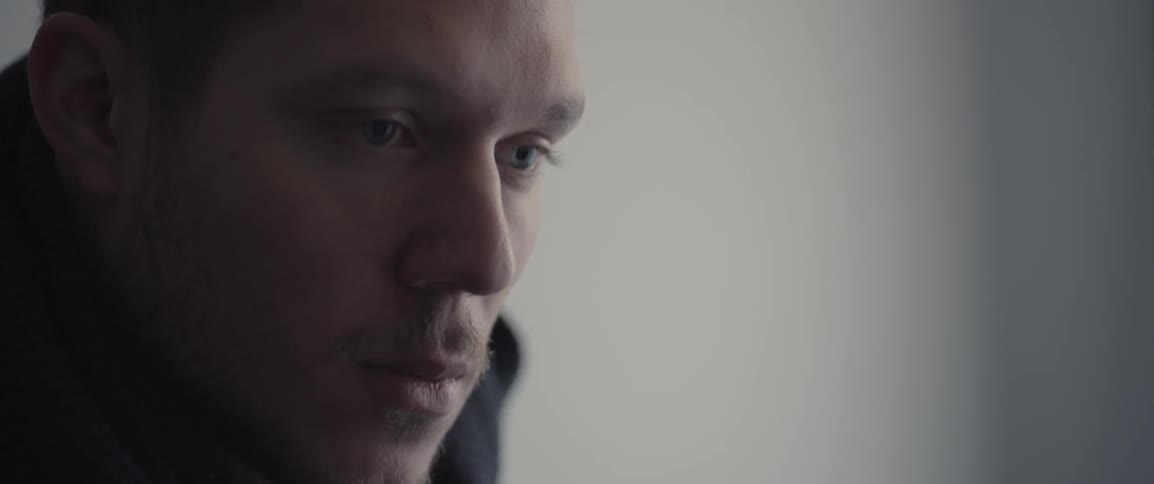 A man looking downward, raises his eyes and looks straight ahead