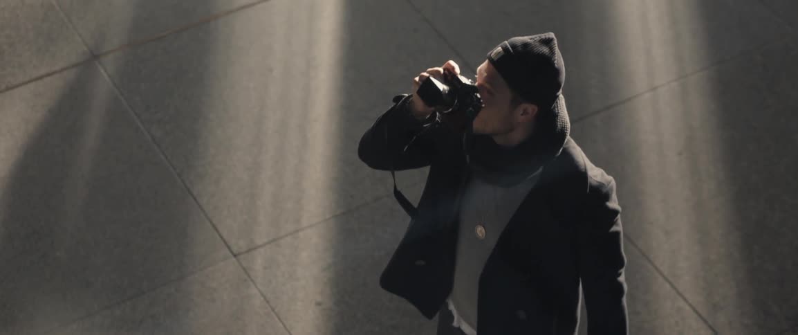 A man takes a photograph on a sidewalk