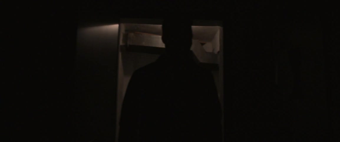 A man walks down a dark hall