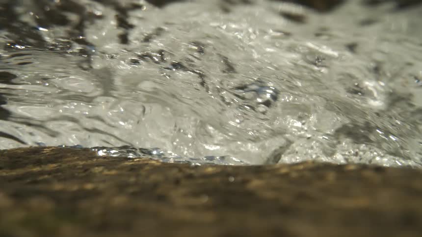 The stream flows over the brown dirt
