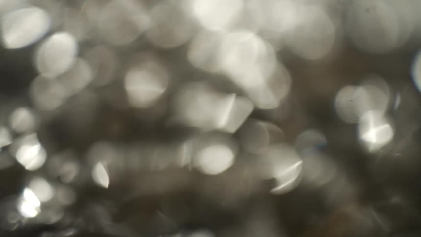 Blurred texture of moving water with shimmering reflections