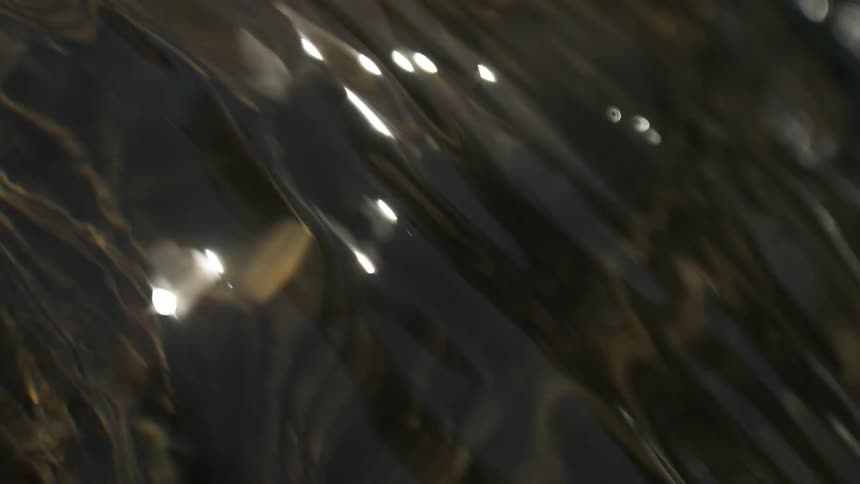 The sun is reflecting on the water moving in the stream