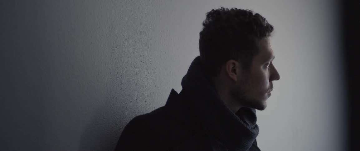 A man leans against a building wall