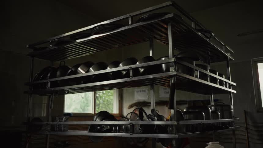 Pots and pans are stacked on shelves in a closed restaurant kitchen