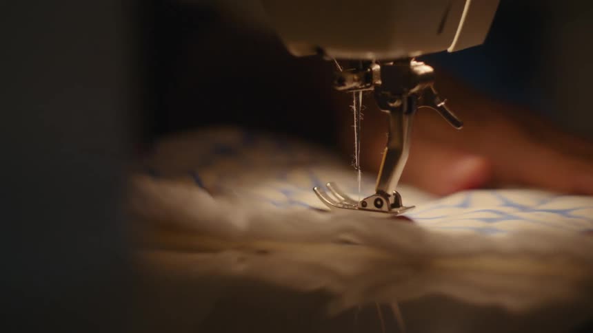 Sewing being done on a machine with hands guiding the fabric