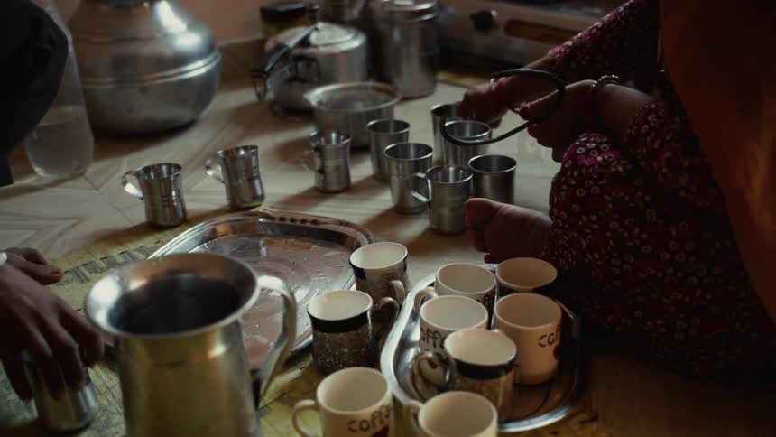People arrange metal and ceramic utensils on floor of domestic area with container and hose