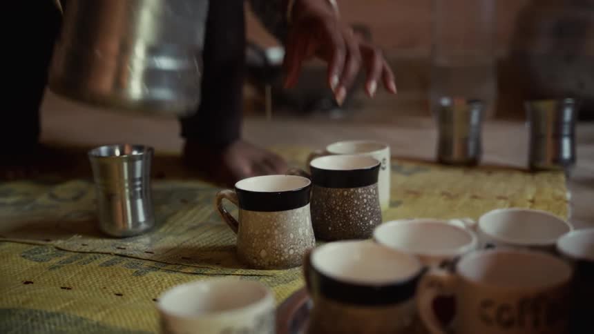 The woman is filling mugs with coffee