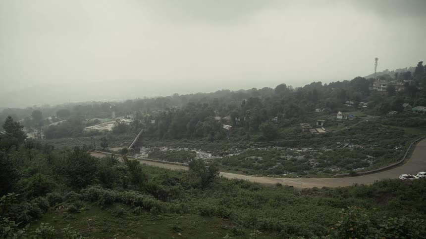A suburban area at midday with cars parked along the roadside and grass lining the street