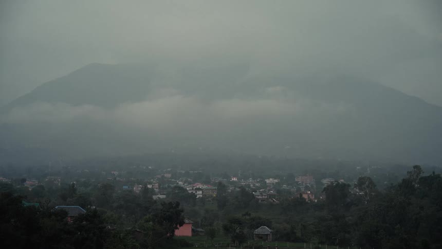 Rain clouds hang low over a mountain town