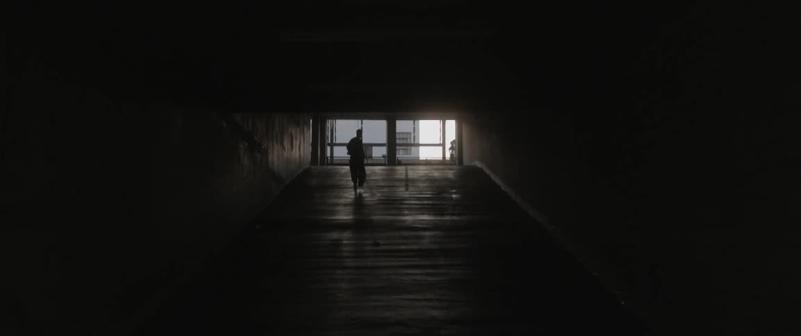 A man is running down a long dark hall