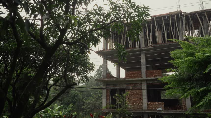 A concrete structure with some brick walls being built and several beams supporting the upper floor