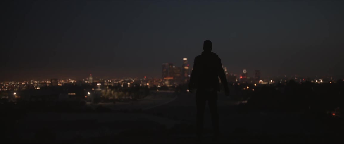 A man throws an item towards a city at dawn