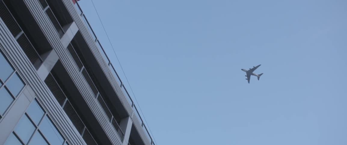 A jet flies over a building