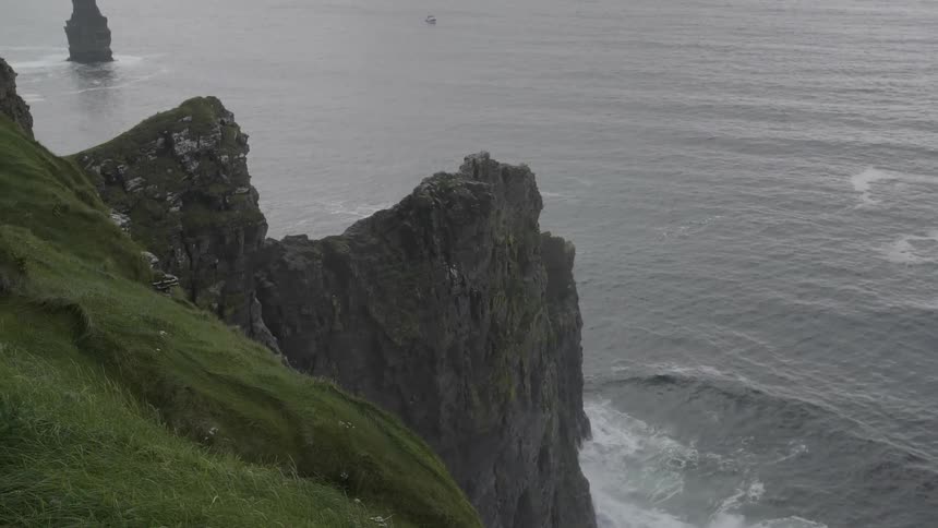 The waves crash against the very steep cliff