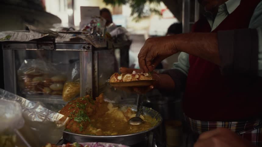 An indian vendor prepares street food at an outdoor stall