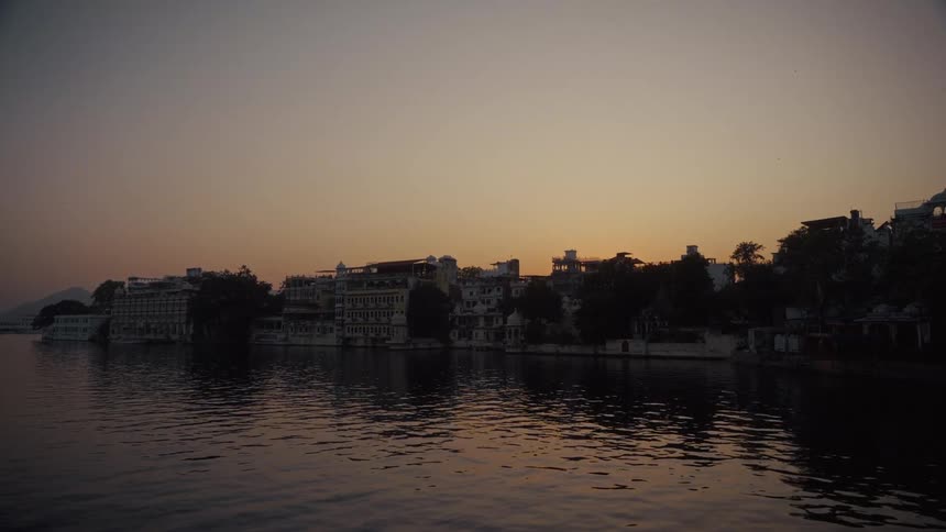 Waterside cityscape appears under an orange sky at sunset