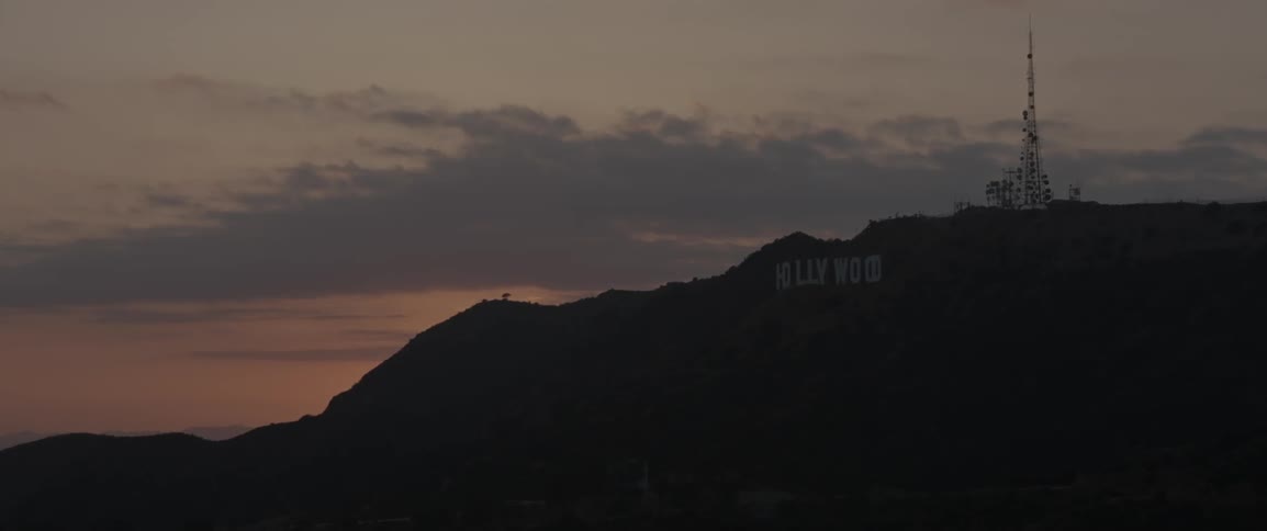The hollywood sign sits on the top of the hill at sunset