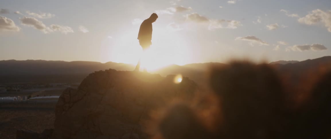 A man is standing on some rocks at sunset