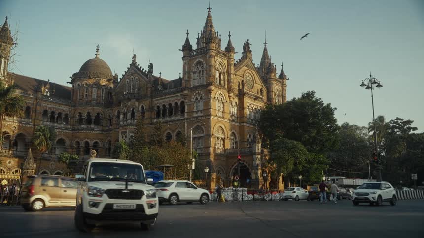 Historic railway station displays victorian gothic architecture amid urban traffic and clear sky