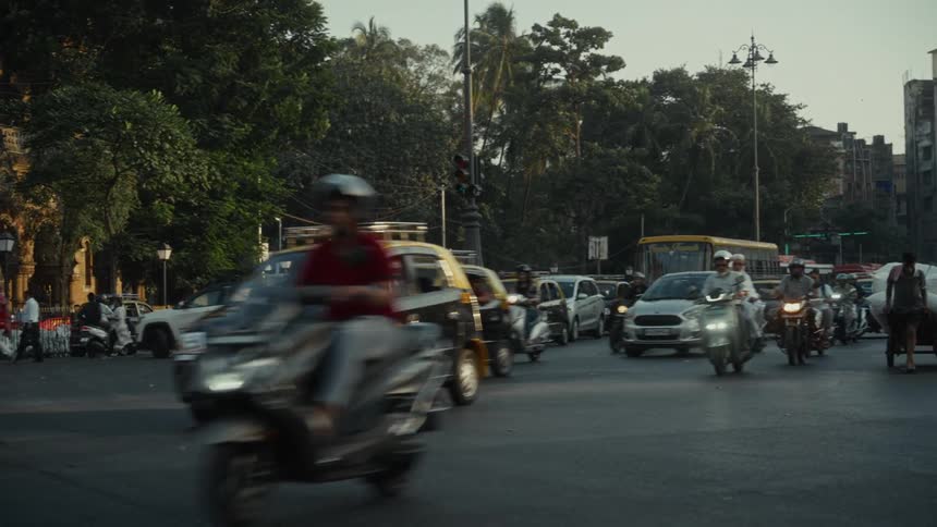 The video captures a busy street scene with heavy traffic in an urban area likely in india given the presence of yellowandblack taxis and various motorbikesnumerous vehicles including cars motorbikes and a school bus move quickly through an inte